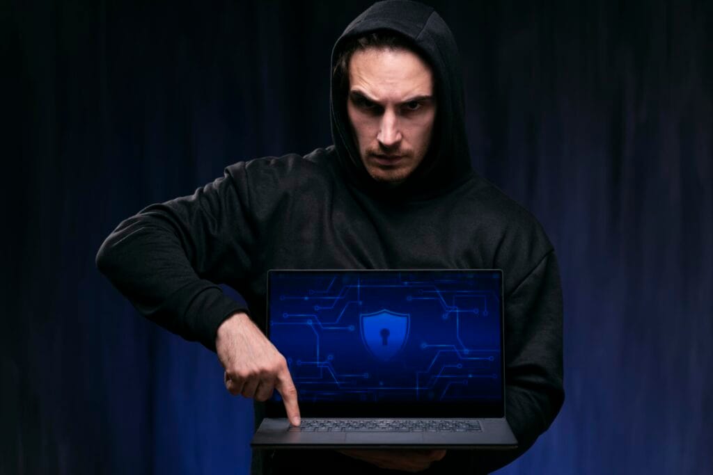 a man in a black hoodie holding a laptop